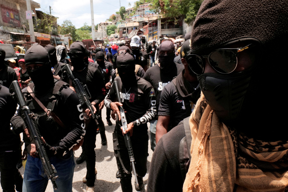 Des membres armés et masqués d’un gang marchent dans une rue en Haïti.