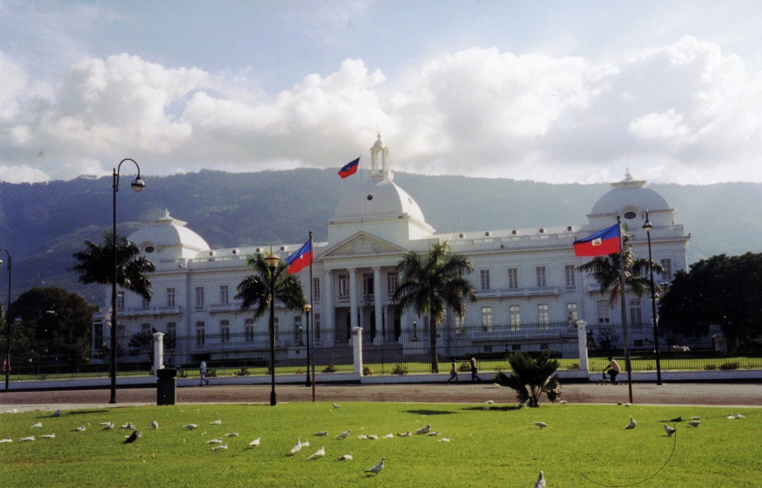 Le Palais national d’Haïti avant le séisme de 2010, derrière une pelouse où flottent plusieurs drapeaux haïtiens.